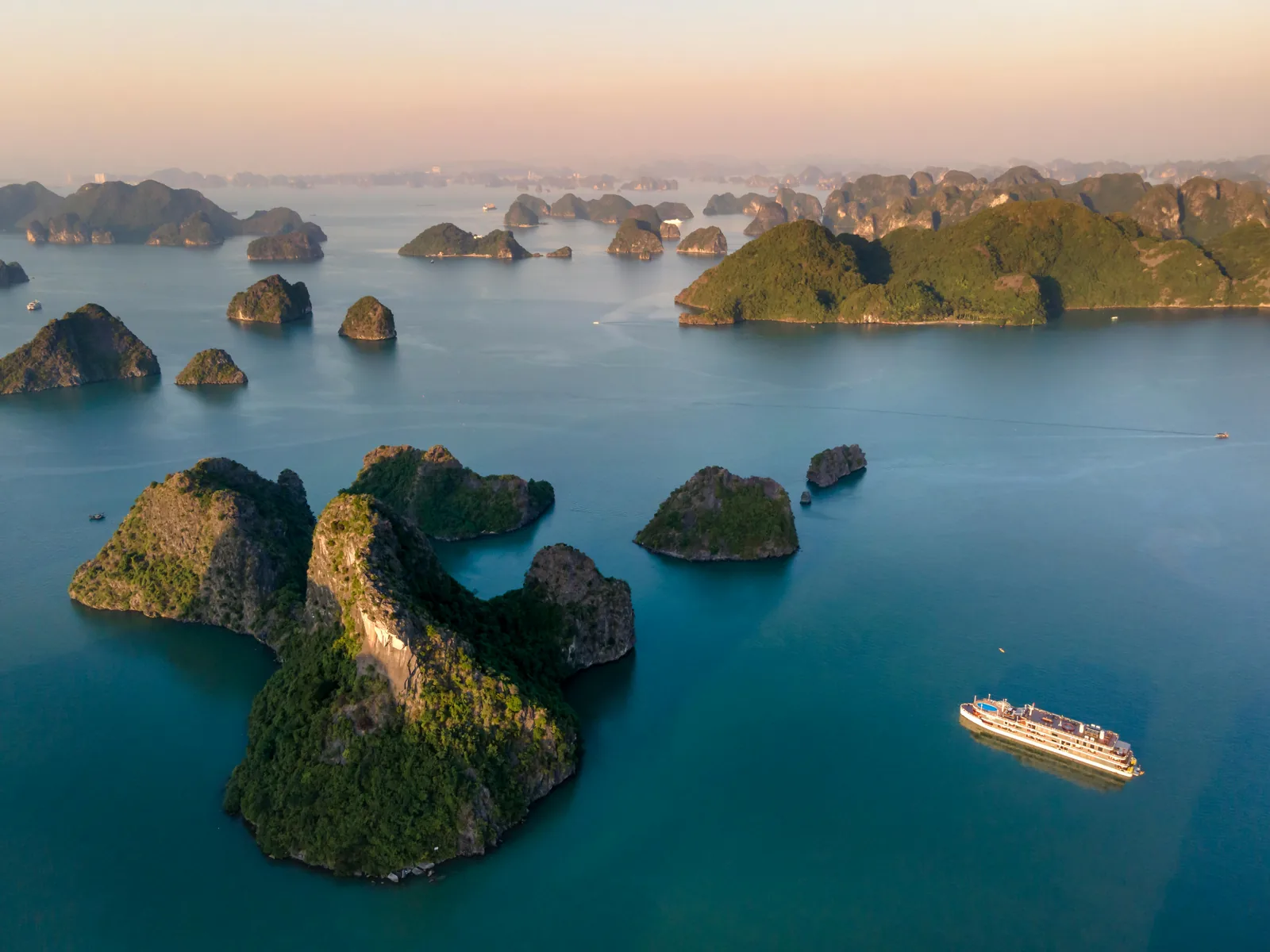 Pitons karstiques de la Baie d'Ha Long au lever du soleil avec jonques en bois, Vietnam